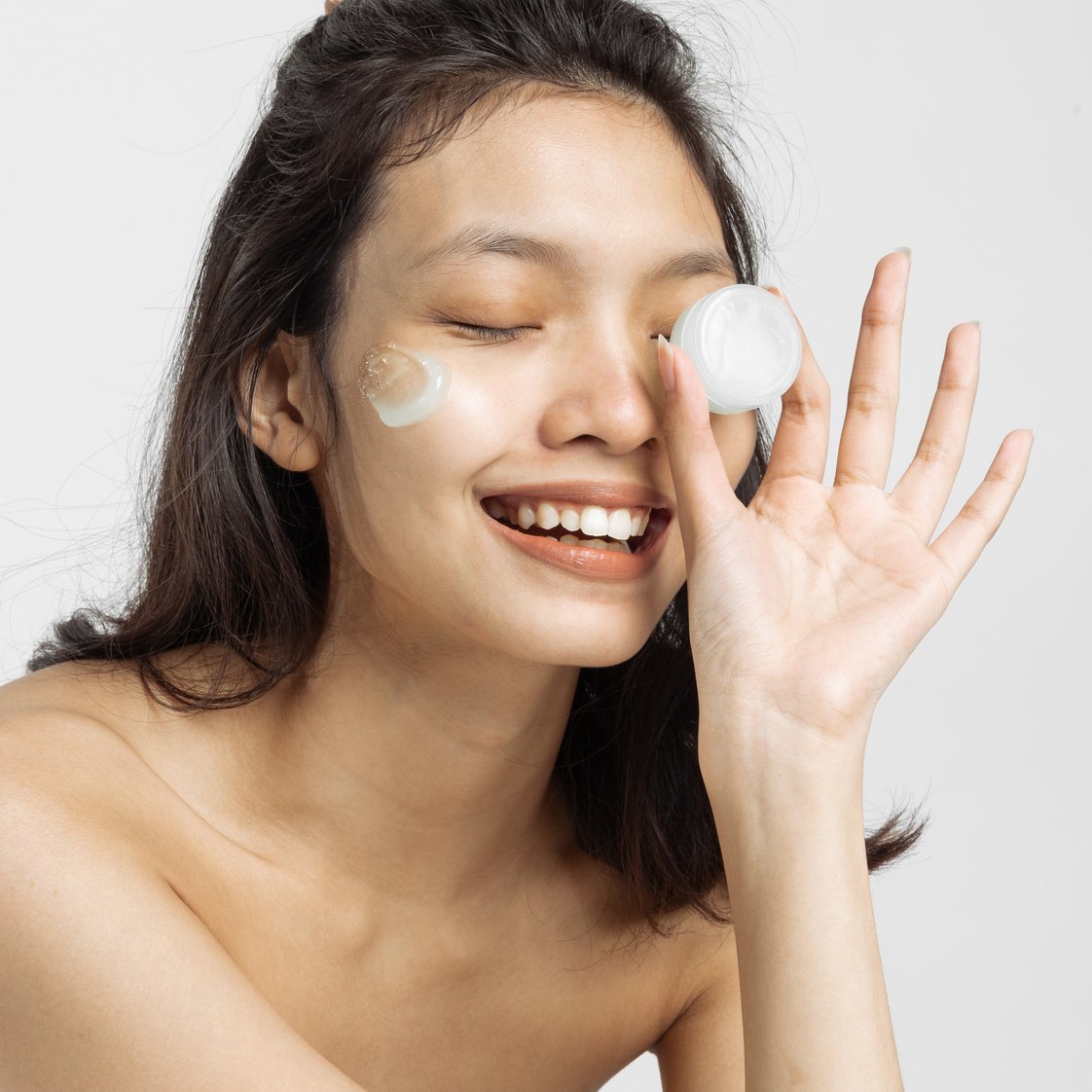 Smiling Woman with Facial Moisturizer Holding a Cosmetic Container